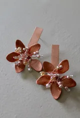 Caravanas artesanales en tono cobre, con diseño de flor metálica y centro decorado con pequeñas cuentas de cristal.