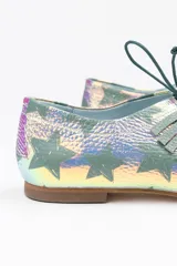 Zapato tipo blucher confeccionado en napa tornasolada con estampado de estrellas en color verde agua. Presenta un adorno artesanal de flecos en napa verde sobre el empeine, cierre con cordones, interior en piel y suela de cuero.