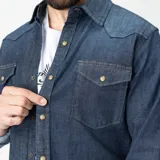 Camisa de denim azul con cuello clásico, cierre con botones a presión, mangas largas con puños abotonados y dos bolsillos con solapa abotonada en el pecho. Corte regular.