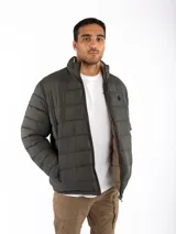 Campera puffer reversible color verde azulado con interior gris. Tiene cuello alto, cierre frontal y bolsillos laterales con cierre.