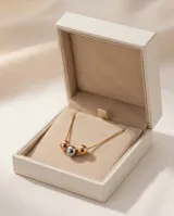 Collar de acero con cadena fina y tres dijes centrales en forma de esferas con acabados en plateado, dorado y oro rosa.