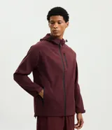 Campera deportiva Get Over de hombre, color bordó, con capucha ajustable, cierre frontal y bolsillos con cremallera. Confeccionada en tejido técnico resistente al agua.