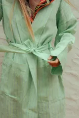 Bata de lino con diseño a rayas verticales en tonos verde menta y azul, de corte holgado, manga larga y lazo ajustable en la cintura.