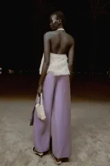 Pantalón de tiro alto con diseño cruzado tipo pareo, pernera ancha y detalle de lazada lateral. Presenta un acabado con efecto brillante.