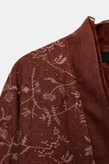 Kimono color ladrillo con bordado floral, confeccionado en lino. Tiene mangas largas, cinturón ajustable con lazadas y detalle de abalorios.