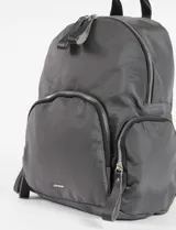 Mochila de diseño funcional en color verde oliva, confeccionada en poliéster. Cuenta con un compartimento principal amplio, un bolsillo frontal con cierre y dos bolsillos laterales con cierre. Incluye manija superior y tiradores de cierre en cuero sintético negro.
