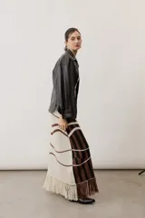 Vestido largo de punto con diseño geométrico y de ondas en color negro y crudo, sin mangas, con escote halter y detalle de flecos en el ruedo.