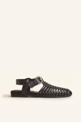 Sandalias planas tipo huarache de cuero negro, con tiras entrelazadas a mano y tira ajustable en el talón con hebilla metálica.