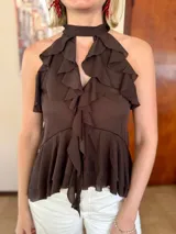 Blusa color marrón chocolate con escote halter, diseño sin mangas y múltiples volados verticales y horizontales que aportan volumen y movimiento.