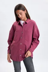 Sobrecamisa de denim color bordó, de corte oversize, con mangas largas, bolsillos frontales con solapa y cierre de botones metálicos.
