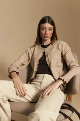 Cárdigan beige de manga larga, tejido liviano y suave, con volados en el delantero, ruedo y puños. Cierre frontal con botones.