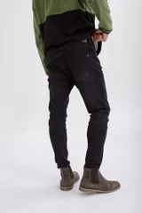 Pantalón de jean corte slim fit en color negro lavado, con cierre de botón y cremallera, y bolsillos laterales y traseros.