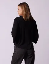 Blusa negra de seda fría, marca Rio & Rian, con escote en V y aplique de crochet en la parte delantera.