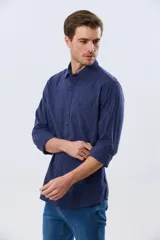 Camisa de lino de manga larga en color beige, con cuello camisero, cierre frontal de botones y un bolsillo ojal en el pecho.