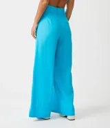 Pantalón pantalona de lino color celeste, de tiro alto, con bolsillos laterales y aberturas frontales en el ruedo.