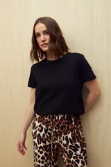 Remera de manga corta confeccionada en algodón liviano con textura sutil, cuello redondo a la base y pequeños tajos laterales en el ruedo.