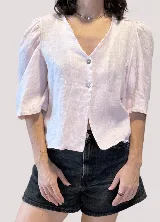 Blusa de lino color rosado, con escote en V, mangas abullonadas 3/4 y cierre frontal con botones.