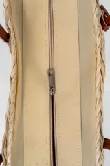 Bolso playero tipo tote de paja color beige con asas de cuero marrón.