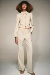 Pantalón de tiro alto con trabillas, bolsillos laterales y cierre frontal con cremallera y gancho metálico. Presenta un diseño de corte recto con costuras decorativas a contraste en la cintura y el ruedo.