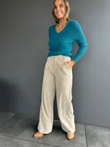 Pantalón de pana en color beige, de corte recto y tiro alto, con pinzas frontales y pretina.