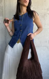 Chaleco de denim azul con escote en V y cierre frontal con botones. Tiene dos bolsillos frontales a la altura de la cintura.