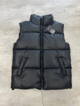 Chaleco puffer de cuero sintético en color negro, con cierre frontal y cuello alto. Diseño acolchado con costuras horizontales.