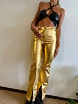 Pantalón dorado de tiro alto, corte ajustado hasta la rodilla y acampanado con aberturas en el ruedo.