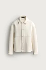 Sobrecamisa boxy fit color beige, confeccionada en tejido compacto, con cuello solapa, bolsillos delanteros de parche y cierre frontal con botones.