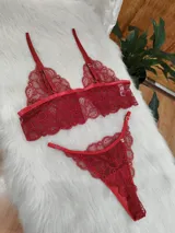 Conjunto de lencería de dos piezas confeccionado en encaje rojo. Incluye un bralette estilo top con breteles regulables y una tanga con laterales ajustables.