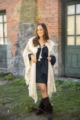 Ruana de tejido liviano color beige, con diseño abierto y detalles de volados en mezcla de lino y algodón. Presenta terminaciones con flecos en el ruedo y cordones decorativos con borlas en el frente.