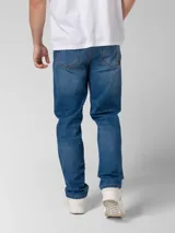 Pantalón de jean azul índigo con diseño clásico de cinco bolsillos, cierre de cremallera y botón metálico. Presenta corte de pierna delgada, remaches con logo en bolsillos delanteros y parche de marca en la cintura trasera.