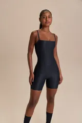 Jumpsuit corto de diseño ajustado con escote cuadrado y breteles finos. Confeccionado en tejido técnico con acabado ligeramente brillante y textura acanalada, ofrece compresión media y alta elasticidad.