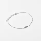 Pulsera plateada de cadena fina con dije de dos esferas y un cristal engarzado.