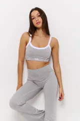 Conjunto deportivo compuesto por un top de escote redondo con breteles blancos y un pantalón largo de corte acampanado, ambos en color gris melange.