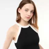Top de punto negro con cuello halter y ribetes blancos en contraste, corte al cuerpo y diseño sin mangas.