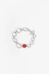 Pulsera de eslabones plateados con cierre de barra y aro, adornada con una piedra circular roja en el centro.