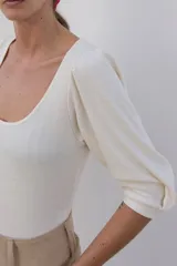 Body de algodón con textura acanalada, color rosado, con escote redondo y mangas largas abullonadas con puños elásticos.