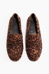 Mocasines tipo náuticos con estampa animal print de leopardo, con detalle de cordones decorativos marrones en el empeine y ojales metálicos dorados.