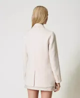 Blazer cruzado de lana color crudo, con solapas, cierre con botones a tono, manga larga con aberturas y bolsillos con solapa.