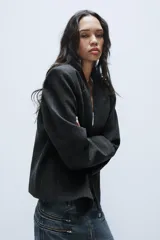 Blazer corto de corte oversize con estampado de cuadros, cuello con solapa de muesca, manga larga y cierre frontal cruzado con un botón. Cuenta con bolsillos decorativos de vivo en el frente y forro interior.