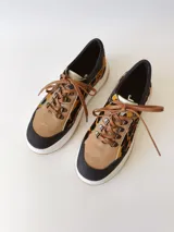 Championes deportivos de cuero con estampado animal print, cordones marrones y suela blanca con base color caramelo.