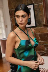 Vestido largo de satén con estampado abstracto en tonos verdes y azules, con escote halter cruzado, detalle de frunce en el pecho y tajo lateral profundo.