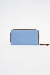 Billetera grande de cuero color celeste con cierre marrón y logo estampado.