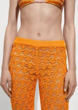 Pantalon de crochet color naranja con diseño de tejido calado, corte flare y cintura elástica.