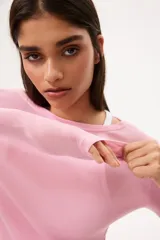 Remera de punto suave, color rosado, con cuello redondo y mangas largas. Presenta un corte entallado y bajo recto.