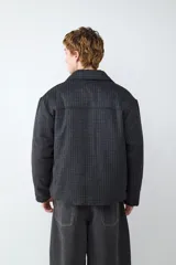 Campera de paño con diseño a cuadros, cuello clásico, cierre frontal con botones metálicos y bolsillos frontales tipo parche.