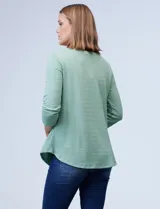 Blusa verde agua en tejido texturado, con cuello redondo y escote en V con aplique de aros metálicos.