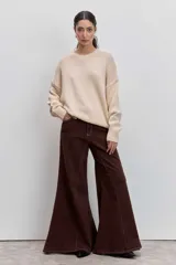 Sweater de punto en color beige, con cuello redondo acanalado, mangas largas con puños ajustados y diseño holgado.