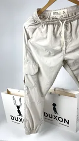 Pantalón cargo color arena con puño elástico en los tobillos, cintura elastizada con cordón ajustable, bolsillos laterales y bolsillos cargo con solapa en los muslos.