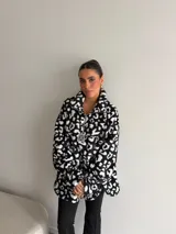 Buzo de peluche con estampado animal print, cuello alto con cierre frontal parcial y detalle de etiqueta decorativa en el pecho.